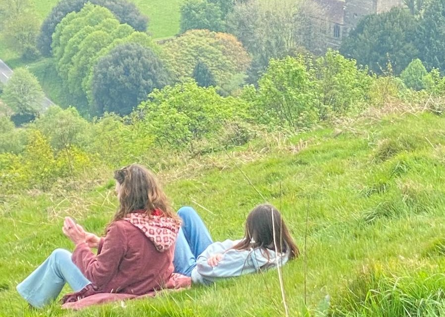 Two people relaxing on a grassy hillside