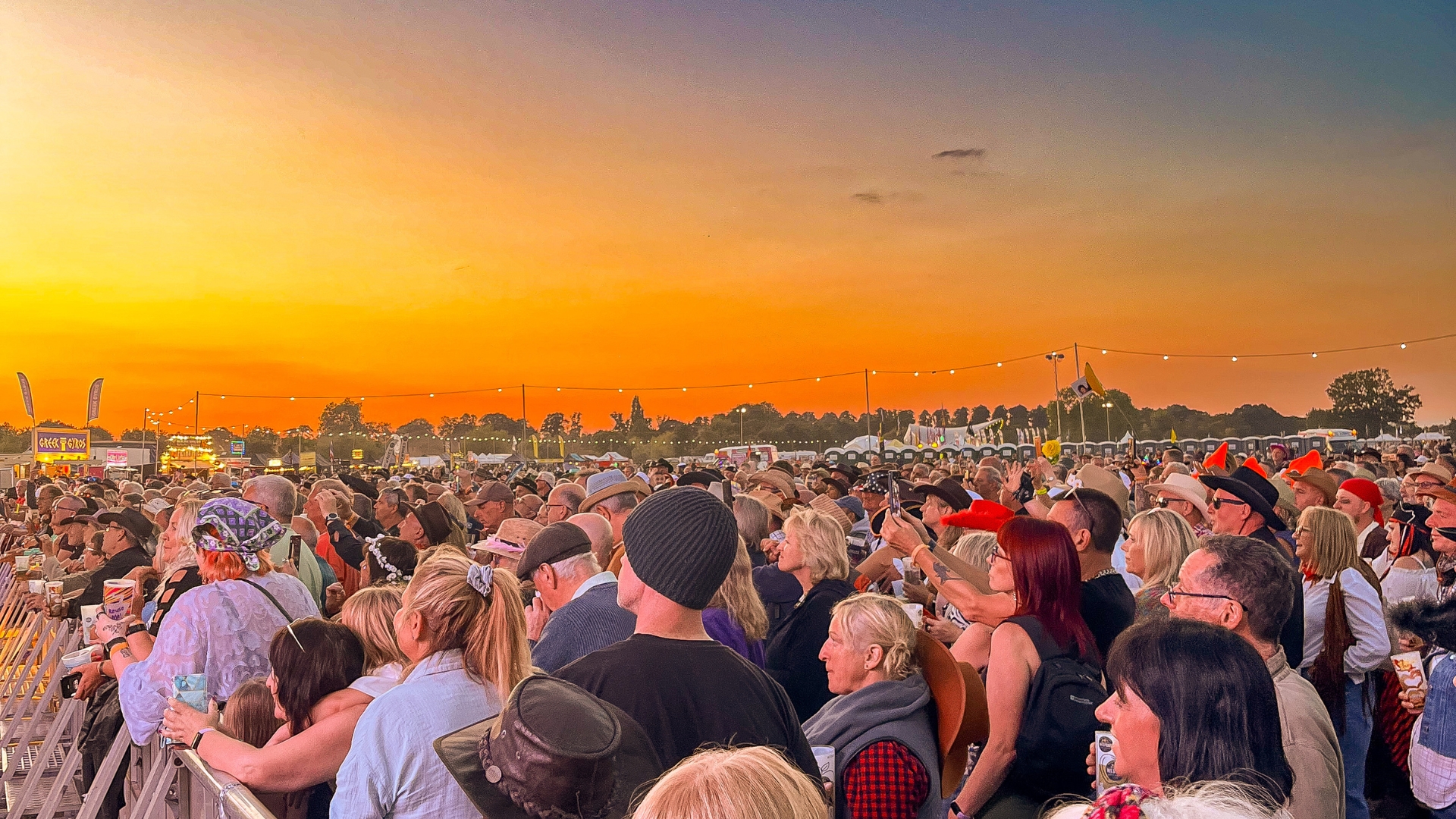 Sunshine Festival crowd beneath a glowing orange sunset